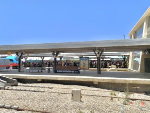 A side view of a train station platform filled with about 80 people. Most of them are male and female soldiers with large bags on their backs.